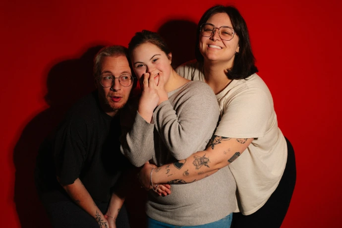 Three friends embracing against a red background
